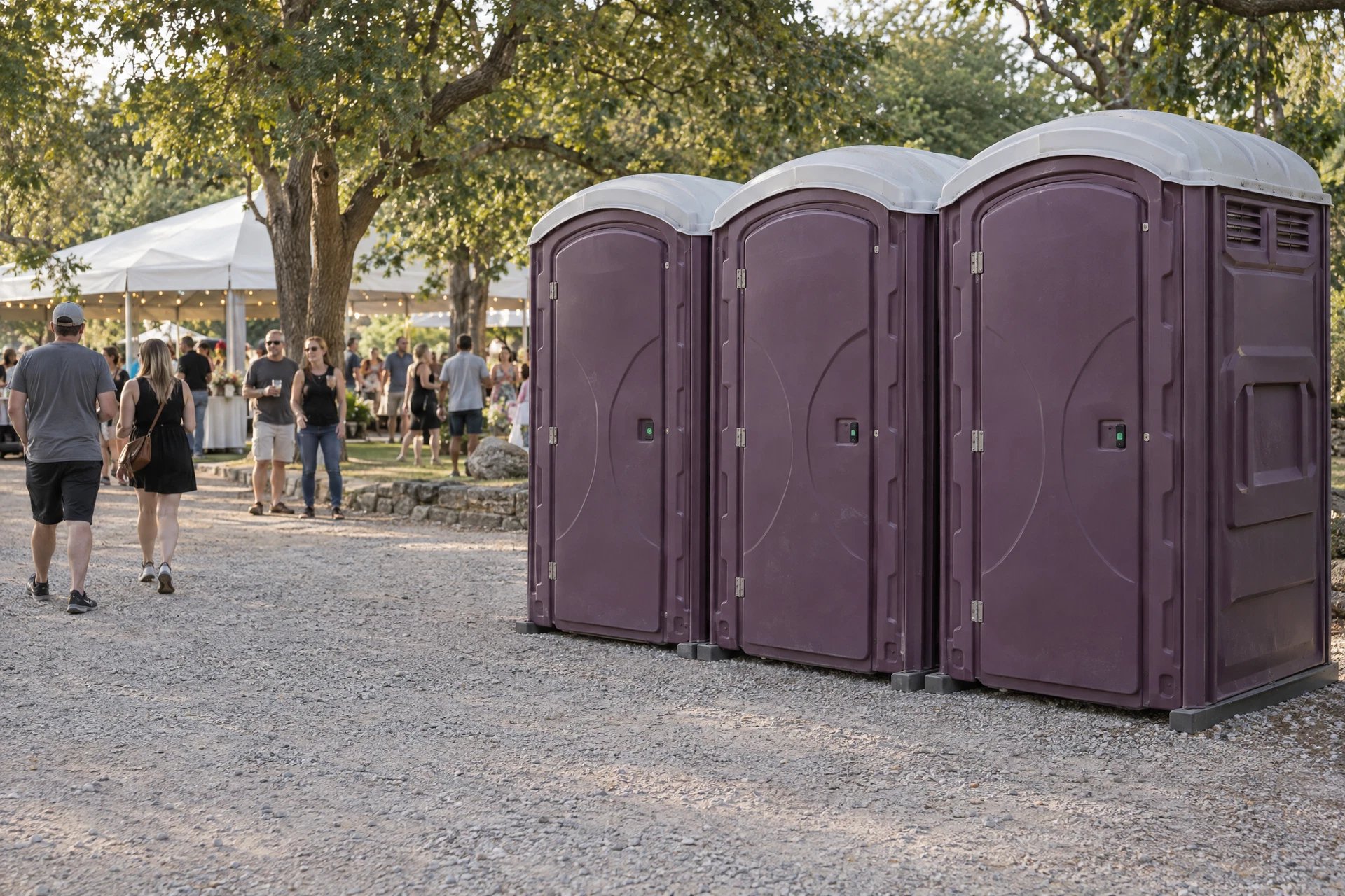 Guests walking beside portable restrooms at an outdoor event