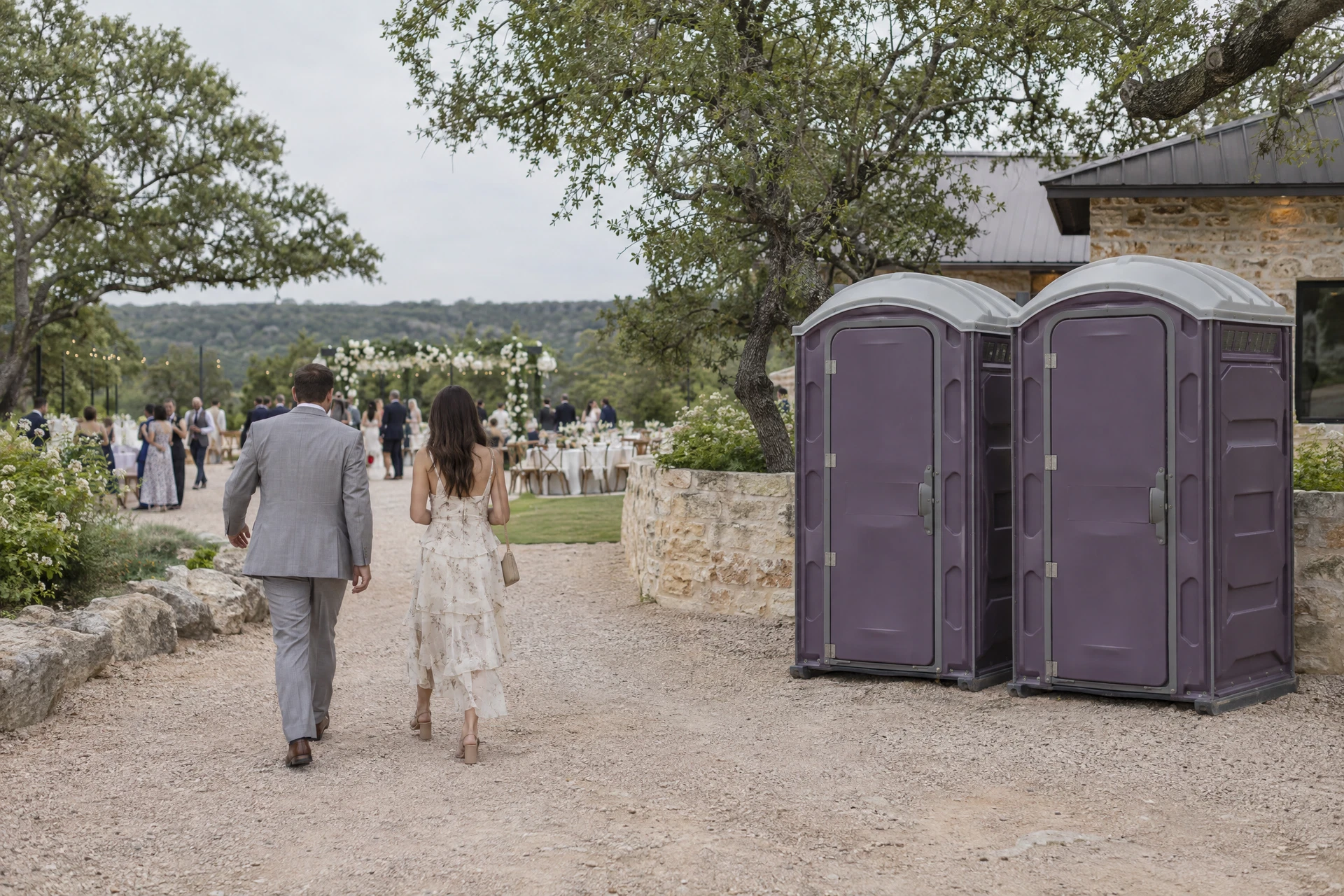 Portable restrooms along a garden wedding walkway